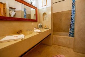 La salle de bains est pourvue d'un lavabo, d'une baignoire et d'un miroir. dans l'établissement Riad Dombaraka, à Marrakech