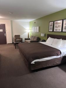 a hotel room with a large bed and a couch at Sleep Inn & Suites Gulfport in Gulfport