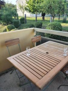 - une table en bois et 2 verres à vin sur le balcon dans l'établissement L'Obernois situé dans 1 résidence privée, à Obernai