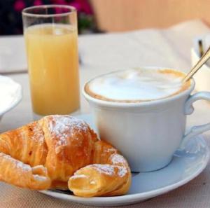 a plate with a cup of coffee and croissants on a table at Central Station Suite Apartment in Bari