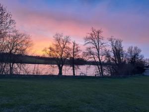 a sunset over a lake with trees in a field at Chez Saliha et Serge in Lamarche-sur-Saône