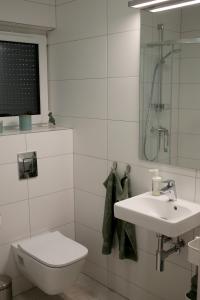 a white bathroom with a toilet and a sink at Apartament Niechorze in Niechorze