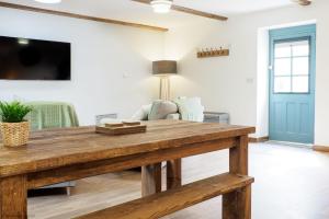 een woonkamer met een houten tafel en een televisie bij Budock Cottage in Mawnan