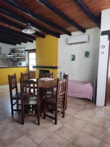 a dining room with a table and chairs and a bed at El Espinillo, Casa de Campo in Santa Rosa de Calamuchita