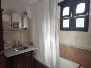 a bathroom with a sink and a shower curtain at El Espinillo, Casa de Campo in Santa Rosa de Calamuchita