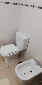 een witte badkamer met een toilet en een wastafel bij Pardelas patagonia in Puerto Madryn