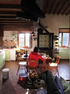 a woman sitting at a table in a kitchen at Loft in Chianti in medieval watermill in Gaiole in Chianti