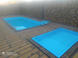 a swimming pool with two blue mats on a wooden floor at Chácara Espaço Feliz in Olímpia