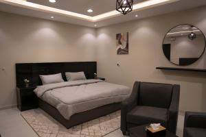 1 dormitorio con cama, silla y espejo en Fans Hotel Suites en Abha