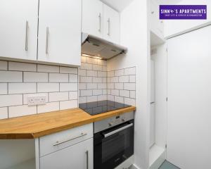 una cocina con armarios blancos y horno negro en 1 Bed Central London Apartment en Londres