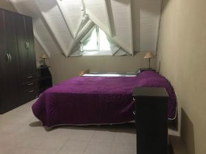 1 dormitorio con cama morada y ventana en Pinamar 497 en Pinamar