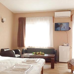 LesnovoにあるLesnovo House Tomevskiのベッド2台、ソファ、テレビが備わる客室です。