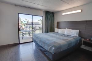 a bedroom with a bed and a balcony with a table at WindWater Hotel and Marina in South Padre Island