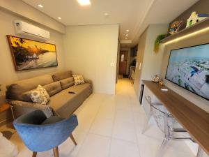 sala de estar con sofá y TV de pantalla plana en Praia dos Carneiros Flat 120-CM Eco Resort - ao lado da igrejinha, en Tamandaré