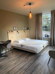 Un dormitorio con una gran cama blanca y una mesa en Bed and Breakfast Stinzenflora, en Cornjum