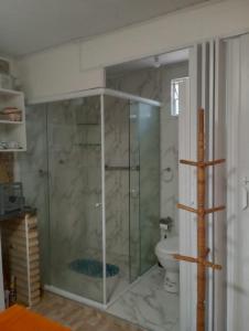 a bathroom with a glass shower and a toilet at Pousada Villa Mariposa in Beberibe