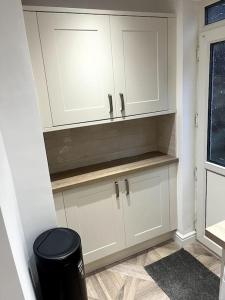 a kitchen with white cabinets and a trash can at Modern welsh cottage in Porth