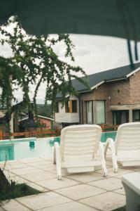 two white chairs sitting next to a swimming pool at Pentagrama, casas de campo in Villa General Belgrano