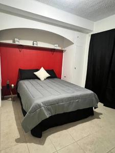 1 dormitorio con 1 cama grande y pared roja en Departamento, recién remodelado a 3 min USA. 2 en Ciudad Juárez