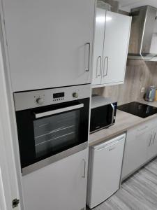 a kitchen with white cabinets and a black oven at A one spacious bedroom apartment in Welling