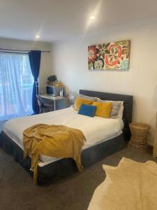 sypialnia z dużym łóżkiem z żółtymi i niebieskimi poduszkami w obiekcie Ange's BnB - Self Contained Unit with Ensuite w mieście Lyndhurst