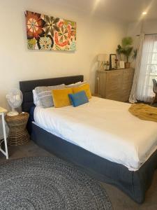 a bedroom with a large bed with yellow and blue pillows at Ange's BnB - Self Contained Unit with Ensuite in Lyndhurst