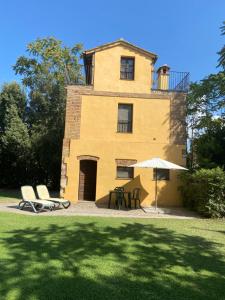 uma casa com duas cadeiras e um guarda-chuva em frente em Agriturismo Relais Villa Passerini em Grosseto