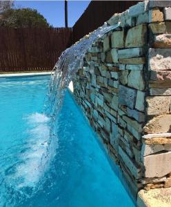 una piscina con una pared de piedra y una fuente de agua en Punta Gaviota Apart en Villa Gesell