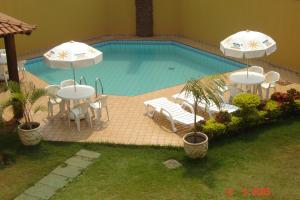 uma piscina com duas mesas e guarda-sóis e cadeiras em Bravo's Hotel em Xinguara