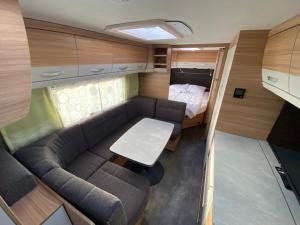 ein kleines Wohnzimmer mit einem Sofa und einem Bett in der Unterkunft Wohnwagenvermietung Sylt in Rantum