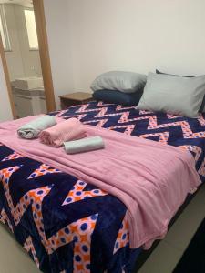 a bed with two pillows and a blanket on it at Apartamento Prainha Arraial in Arraial do Cabo