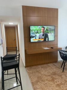 a television on a wall with a man on it at Apartamento Prainha Arraial in Arraial do Cabo