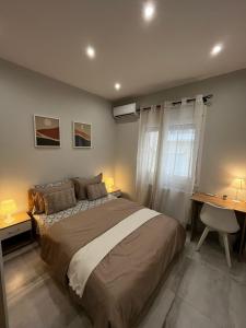 um quarto com uma cama, 2 secretárias e uma janela em Modern flat Ag. Dimitriou em Tessalônica