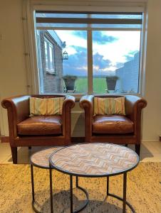 two leather chairs and a table in front of a window at Fila Stroo in Kamperland