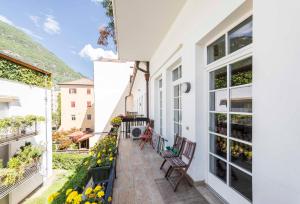 un balcone di una casa con due sedie e fiori di Life Apartment & City Bike a Bolzano