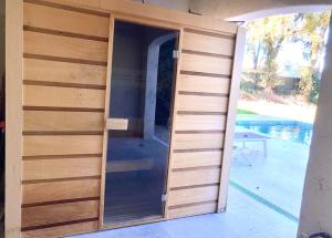 une porte pivotante en bois dans une maison à côté d'une piscine dans l'établissement Maison Piscine Sauna 5min Centre Aix - Casa G., à Aix-en-Provence