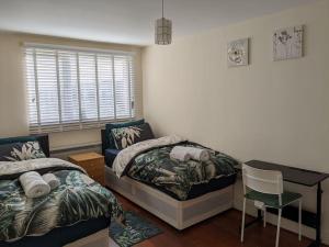 a bedroom with two beds and a desk and a chair at LTK Basildon in Nevendon