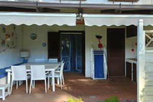 un patio con una mesa y sillas blancas y una puerta azul en Ridente villetta a schiera, 10min a piedi dal mare, en San Felice Circeo