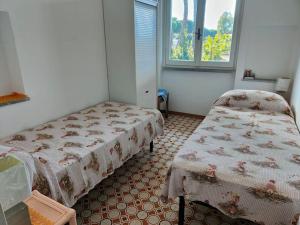 1 dormitorio con 2 camas y ventana en Ridente villetta a schiera, 10min a piedi dal mare, en San Felice Circeo