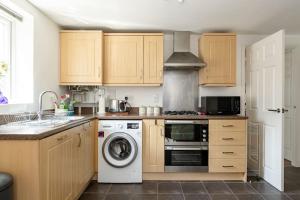 a kitchen with wooden cabinets and a washer and dryer at Modern & Stylish 2 Bedroom Apartment! - Ground Floor - FREE Parking for 2 Cars - Netflix - Disney Plus - Sky Sports - Gigabit Internet - Newly decorated - Sleeps up to 5! - Close to Bournemouth Train Station in Bournemouth