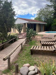 a backyard with wooden benches and a house at La Oma. Casa en Chacras de Coria in Ciudad Lujan de Cuyo