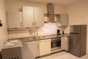 a kitchen with white cabinets and a stainless steel refrigerator at Haus Kim Thinh in Betzdorf +25 photos