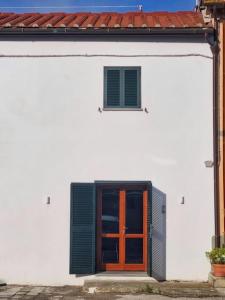 - un bâtiment blanc avec une porte orange et une fenêtre dans l'établissement La casetta di Maty&Fra, à Pistoia