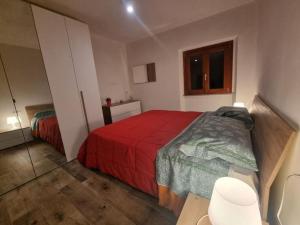 a bedroom with a bed with a red blanket and a table at La casetta di Maty&Fra in Pistoia +3 photos