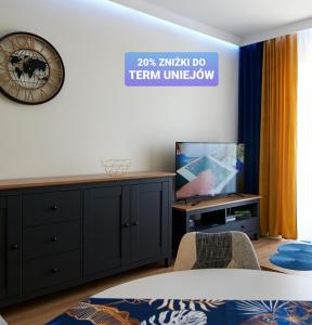 uma sala de estar com televisão e um relógio na parede em Apartament z ogródkiem em Uniejow