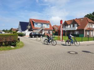 two people riding their bikes down a street at Ferienwohnung Leuchtturm am Sandstrand in Norden