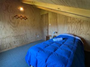 a bedroom with a blue bed with a wooden ceiling at Hospedaje Hamiltons Place in La Ensenada