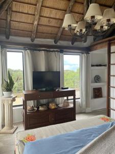 ein Wohnzimmer mit einem TV und 2 Fenstern in der Unterkunft La Roja. Vivir naturaleza, a pasos del océano. in La Pedrera