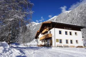 a building in the snow in front of a mountain at Seeberhof in Racines