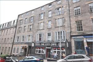 un gran edificio de ladrillo con un cartel para la cafetería de la ciudad en Cosy n Comfy Flat in Historic Heart of Edinburgh, en Edimburgo